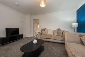 a living room with a couch and a tv at Brancepeth Place in Shildon