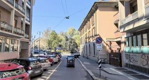 een kleine auto die door een stadsstraat rijdt met geparkeerde auto's bij Apartments Navigli Center in Milaan