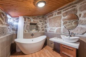 a bathroom with a bath tub and a sink at Stone House in the Peneda-Gerês National Park in Montalegre