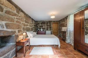 a bedroom with a bed and a stone wall at Stone House in the Peneda-Gerês National Park in Montalegre +88 photos