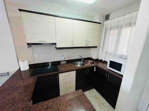 a kitchen with white cabinets and a sink and a microwave at Las Vistas Beach Los Cristianos 2 Swimming Pools in Los Cristianos