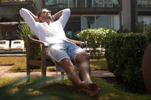 a man laying on a bench with his arms up at Hotel Spa Nau Royal in Camburi