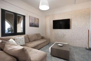a living room with a couch and a flat screen tv at Mythique Pool Residence in Foinikiá