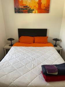 una camera da letto con un letto bianco e cuscini arancioni di El Refujio maison independante avec vraie piscine privée au sel chauffee pas de chlore a Turís Altre 37 foto