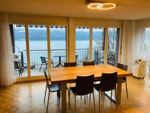 a dining room with a table and chairs and a balcony at Lake View Residence in Niederried