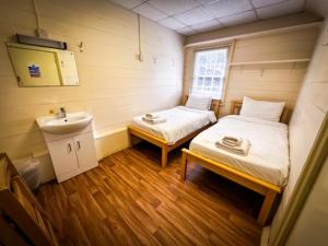 a small room with a bed and a sink at The Bisley Camp Cabins in Guildford