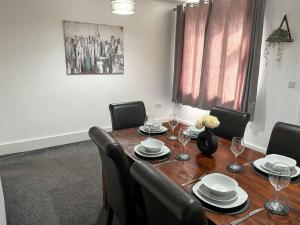 a dining room table with chairs and a wooden table with glasses at 8 Nantwich Road in Crewe