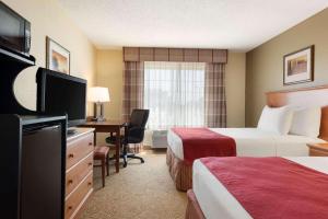 a hotel room with two beds and a desk with a television at Country Inn & Suites by Radisson, Davenport - Quad Cities in Davenport