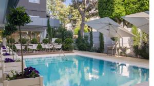 a swimming pool with an umbrella and tables and chairs at Alasia Boutique Hotel in Limassol