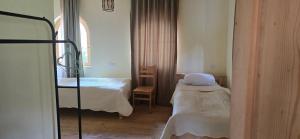 a small room with two beds and a window at Lakhushdi - House of Song in Mestia +11 photos