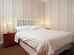 a bedroom with a large white bed and a night stand at Adam Guest House in Perth