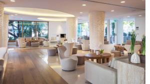 a lobby with white chairs and tables and windows at Alasia Boutique Hotel in Limassol