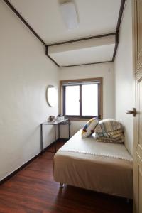 a bedroom with a bed with a window and a table at Jiwoljang Guesthouse in Seoul