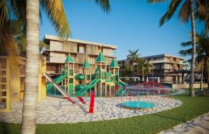 a playground in front of a building with palm trees at Paraíso Porto Alto in Porto De Galinhas