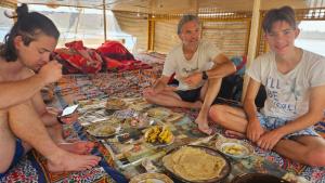 un gruppo di persone seduti intorno a un tavolo con cibo di Kayan Guest House a Aswan Altre 37 foto