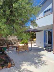 a patio with two benches and an umbrella at I Sette Ulivi Bed and Breakfast in Tergu