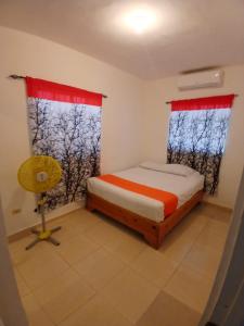 a small bedroom with a bed and two windows at Casa con piscina EN BOCA CHICA in Boca Chica