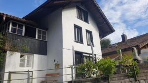 a white house with black windows and a fence at Studio by Apartments Capricorn in Gsteigwiler