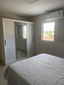 a bedroom with a white bed and a mirror at Comfort and Style White Queen II in Cuiabá