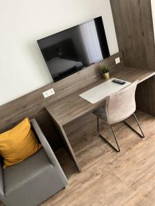 a living room with a desk with a tv and a chair at Living-Apartments-Harsewinkel in Harsewinkel