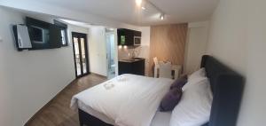 a bedroom with a bed with white sheets and purple pillows at Studio By The Sea 2 in Lepetani