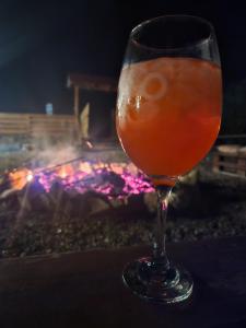 a drink in a glass sitting in front of a fireplace at La Padurea Mica in Cărbunari