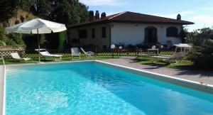 a swimming pool with chairs and an umbrella next to a house at La Guardata in Montefiascone