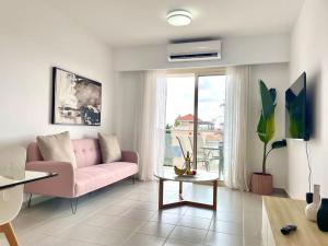 un soggiorno con divano rosa e tavolo di Elysia Park Luxury Apartment a Paphos