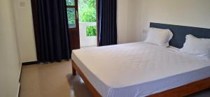 a bedroom with a large white bed with a window at Sandy Steps in Kalutara