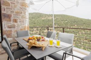 a table with a tray of fruit and two glasses of orange juice at Elaída- Πολυτελής Βίλα-Θέα θάλασσα, Μάνη in Skoutari