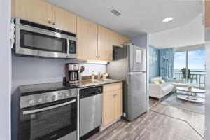 a kitchen with stainless steel appliances and a living room at Oceans One Resort Unit 404 - Oceanfront in Myrtle Beach