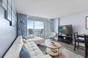 a living room with a couch and a table and a television at Oceans One Resort Unit 404 - Oceanfront in Myrtle Beach
