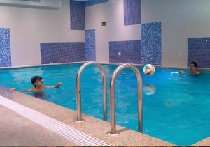 a group of people in a swimming pool with a volley ball at Helat Hotel in Al Khobar