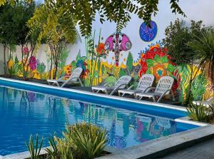 a wall with chairs next to a pool with a mural at Hotel Aiello in San Luis