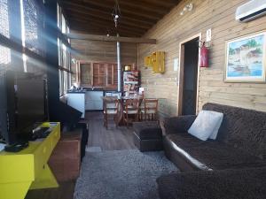 un salon avec un canapé et une salle à manger dans l'établissement Chalé com banheira de hidromassagem e mesa de sinuca, à Bom Jardim da Serra 2 autres photos