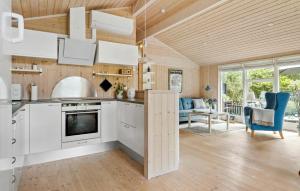 a kitchen and living room with white cabinets and blue chairs at 2 Bedroom Cozy Home In Højslev in Højslev