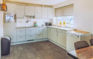 a kitchen with white cabinets and a table at Kraaijennest in Uitgeest
