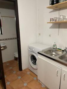 a bathroom with a sink and a washing machine at Spacious ground floor apartment in town centre in Hendaye