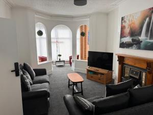 a living room with couches and a tv and a fireplace at Pinnacle Hotel & Suites formerly Jean Martyn Hotel Near Central Blackpool, Near Beach & Attractions in Blackpool