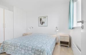 Un dormitorio blanco con una cama y una mesita de noche. en Gudhjem Søpark Lejl 12, en Gudhjem