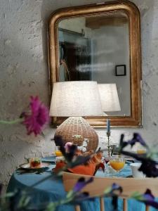 un tavolo con lampada, specchio e fiori di La Robinière Maison d'Hôtes a Mont-près-Chambord