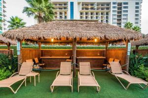Un grupo de sillas y una sombrilla grande. en 1801 Sapphire Beachfront 3 Bedroom Condo, en South Padre Island
