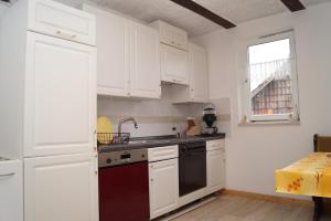 Una cocina con gabinetes blancos y un horno de estufa. en Alte Schule, en Bad Wildungen