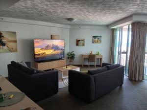 a living room with couches and a flat screen tv at Wings 2 Bedroom Apartment in Gold Coast +5 photos