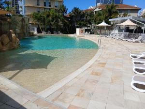 a swimming pool with chairs in a resort at Wings 2 Bedroom Apartment in Gold Coast