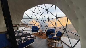 a room with a bed and chairs and a window at We Are Made Of Stories in Joshīmath