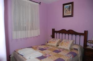 a bedroom with a bed with purple walls and a window at Casa El Rincón del Ángel in Bubión