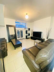 a living room with a leather couch and a television at London Stays Whitechapel in London