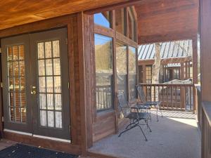 a screened in porch with two chairs and glass doors at Cabin 41 in Almont