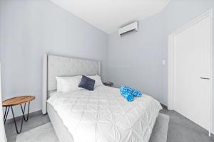 a white bedroom with a white bed with blue pillows at Luxury 1br Getaway Wpool In Washington By Lucha in Palm-Eagle Beach +14 photos